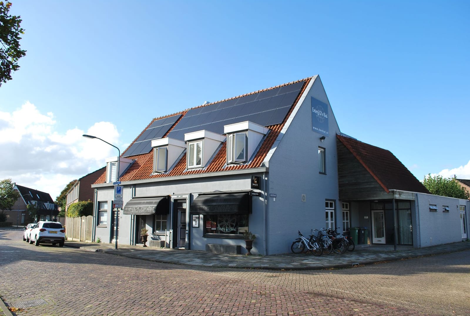 Hoekpand van Eterij d’n Bal met zonnepanelen op het dak en fietsen voor de deur