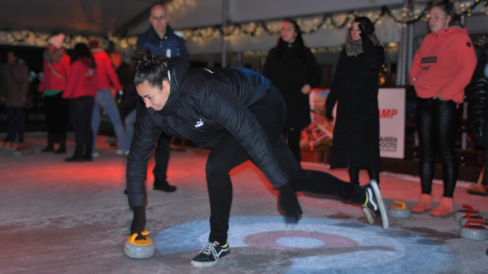 Bezoeker schuift een curlingsteen over het ijs op De IJsmarkt
